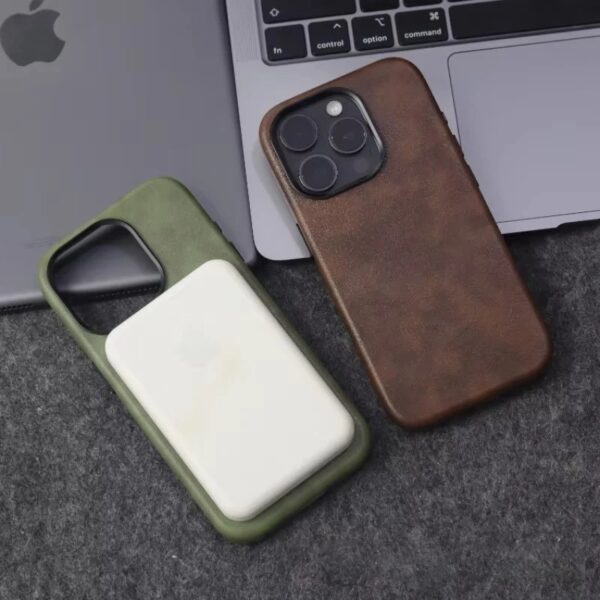 Two leather iPhone cases next to a laptop